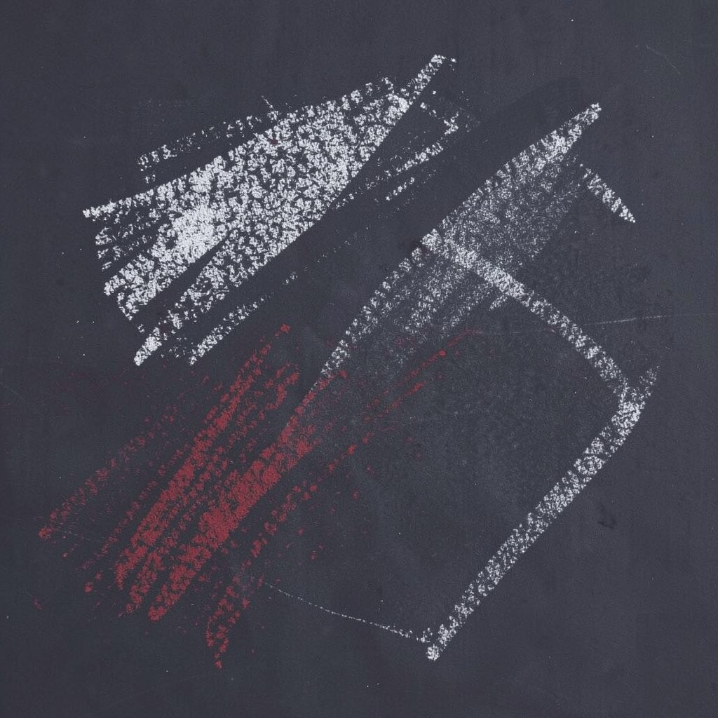 A chalk drawing on a dark slate board of a simple television screen outline with a play triangle sketched in white chalk lines